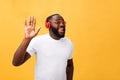 Young African American man wearing headphone and enjoy music over yellow gold Background Royalty Free Stock Photo