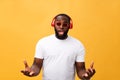 Young African American man wearing headphone and enjoy music over yellow gold Background Royalty Free Stock Photo