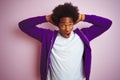 Young african american man wearing purple sweatshirt standing over isolated pink background Crazy and scared with hands on head, Royalty Free Stock Photo