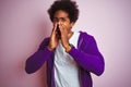 Young african american man wearing purple sweatshirt standing over isolated pink background Shouting angry out loud with hands Royalty Free Stock Photo