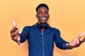 Young african american man wearing sportswear and headphones looking at the camera smiling with open arms for hug Royalty Free Stock Photo