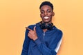 Young african american man wearing sportswear and headphones smiling cheerful pointing with hand and finger up to the side Royalty Free Stock Photo