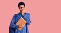 Young african american man wearing student backpack holding book looking stressed and nervous with hands on mouth biting nails Royalty Free Stock Photo