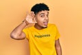 Young african american man wearing t shirt with happiness word message smiling with hand over ear listening an hearing to rumor or