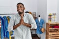 Young african american man working as manager at retail boutique begging and praying with hands together with hope expression on