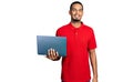 Young african american man working using computer laptop looking positive and happy standing and smiling with a confident smile Royalty Free Stock Photo