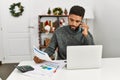 Young african american man working using laptop and talking on the smartphone at home Royalty Free Stock Photo