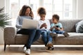 Young black family sit on couch using gadgets Royalty Free Stock Photo