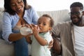 Young African American parents feeding child from bottle Royalty Free Stock Photo