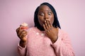 Young african american plus size woman with braids eating sweet chocolate cupcake cover mouth with hand shocked with shame for Royalty Free Stock Photo