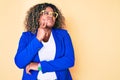 Young african american plus size woman wearing business jacket and glasses thinking concentrated about doubt with finger on chin Royalty Free Stock Photo