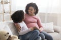 Young pregnant black woman reading book with little daughter at home Royalty Free Stock Photo