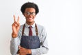 Young african american shopkeeper man wearing apron glasses over isolated white background smiling with happy face winking at the Royalty Free Stock Photo