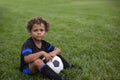 Young African American soccer player sitting on a grass field expressionless before a soccer game Royalty Free Stock Photo
