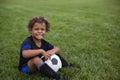 Young African American soccer player sitting on a grass field smiling before a soccer game Royalty Free Stock Photo