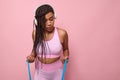 Young African American sporting woman in pink tracksuit, concentrate on doing exercises on arms with elastic resistance fitness