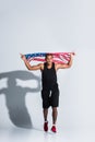 young african american sportsman holding american flag and running