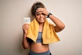 Young african american sportswoman wearing towel holding reminder with diet message stressed with hand on head, shocked with shame Royalty Free Stock Photo