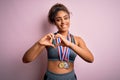 Young african american sporty girl doing sport winning medals over isolated pink background smiling in love showing heart symbol Royalty Free Stock Photo