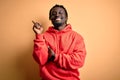 Young african american sporty man wearing sweatshirt with hoodie over yellow background with a big smile on face, pointing with Royalty Free Stock Photo