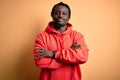 Young african american sporty man wearing sweatshirt with hoodie over yellow background happy face smiling with crossed arms Royalty Free Stock Photo