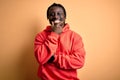 Young african american sporty man wearing sweatshirt with hoodie over yellow background looking confident at the camera smiling Royalty Free Stock Photo