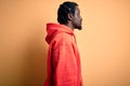 Young african american sporty man wearing sweatshirt with hoodie over yellow background looking to side, relax profile pose with Royalty Free Stock Photo