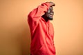 Young african american sporty man wearing sweatshirt with hoodie over yellow background very happy and smiling looking far away Royalty Free Stock Photo