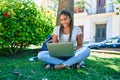 Young african american student woman smiling happy using computer laptop sitting on the grass at the university campus Royalty Free Stock Photo