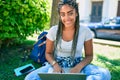 Young african american student woman smiling happy using computer laptop sitting on the grass at the university campus Royalty Free Stock Photo