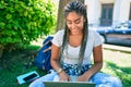 Young african american student woman smiling happy using computer laptop sitting on the grass at the university campus Royalty Free Stock Photo