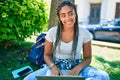 Young african american student woman smiling happy using computer laptop sitting on the grass at the university campus Royalty Free Stock Photo
