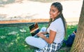 Young african american student woman smiling happy using computer laptop sitting on the grass at the university campus Royalty Free Stock Photo