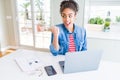 Young african american student woman using computer laptop pointing and showing with thumb up to the side with happy face smiling Royalty Free Stock Photo