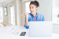 Young african american student woman using computer laptop pointing and showing with thumb up to the side with happy face smiling Royalty Free Stock Photo