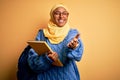 Young African American student woman wearing muslim hijab and backpack holding book smiling friendly offering handshake as Royalty Free Stock Photo