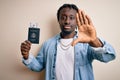 Young african american tourist man holding passport with dollars banknotes as money travel with open hand doing stop sign with Royalty Free Stock Photo