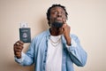 Young african american tourist man holding passport with dollars banknotes as money travel serious face thinking about question,