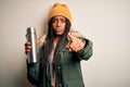 Young african american tourtist woman wearing coat and drinking water from thermo pointing with finger to the camera and to you, Royalty Free Stock Photo