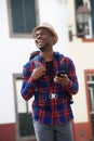 Young african american travel man laughing with mobile phone while walking on street with backpack Royalty Free Stock Photo