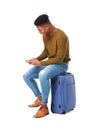 Young african american travel man sitting on suitcase with mobile phone Royalty Free Stock Photo