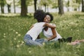 Young african-american twin sisters sitting on a grass in a park and hugging Royalty Free Stock Photo