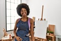 Young african american woman with afro hair at art studio looking away to side with smile on face, natural expression Royalty Free Stock Photo