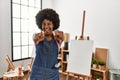 Young african american woman with afro hair at art studio pointing to you and the camera with fingers, smiling positive and Royalty Free Stock Photo