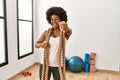 Young african american woman with afro hair at the gym training with battle ropes pointing to you and the camera with fingers, Royalty Free Stock Photo