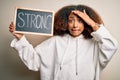 Young african american woman with afro hair holding blackboard with strong message stressed with hand on head, shocked with shame Royalty Free Stock Photo