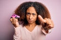 Young african american woman with afro hair holding with hand small pink toy car pointing with finger to the camera and to you, Royalty Free Stock Photo