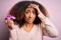 Young african american woman with afro hair holding with hand small pink toy car stressed with hand on head, shocked with shame Royalty Free Stock Photo