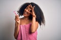 Young african american woman with afro hair in a towel holding female razor for body depilation with happy face smiling doing ok