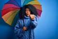 Young african american woman with afro hair under colorful umbrella for winter weather rain pointing with finger to the camera and Royalty Free Stock Photo